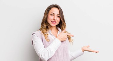 Güzel bir kadın gülümsüyor, mutlu, kaygısız ve tatmin olmuş hissediyor, fotokopi alanındaki konsepte veya fikre işaret ediyor.