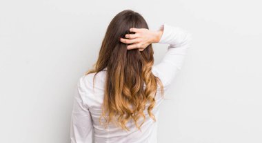 Güzel bir kadın düşünüyor ya da şüphe ediyor, kafasını kaşıyor, kafası karışık ve kafası karışık hissediyor, geriye ya da arkaya bakıyor.