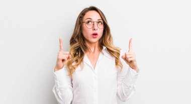 Güzel bir kadın şaşırmış, şaşırmış ve ağzı açık görünüyor, iki eliyle uzayı işaret ediyor.