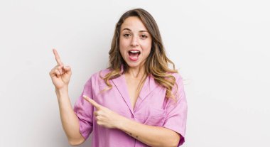 Güzel bir kadın mutlu ve şaşırmış hissediyor, şok olmuş bir ifadeyle gülümsüyor ve bir tarafı işaret ediyor.