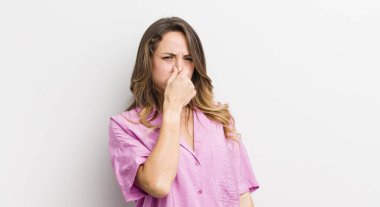 Güzel bir kadın iğreniyor, kötü ve nahoş bir koku duymamak için burnunu tutuyor.