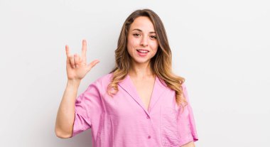 Güzel bir kadın kendini mutlu, eğlenceli, kendinden emin, pozitif ve asi hissediyor, elle rock veya heavy metal işareti yapıyor.