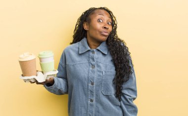 Siyah güzel bir kadın omuz silkiyor, kafası karışık ve kararsız.