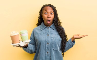 siyah güzel kadın şaşırmış ve şok olmuş görünüyor, çenesi düşmüş bir nesne tutuyor.