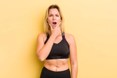 Sarışın, güzel bir kadın. Ağzı ve gözleri açık, elleri çenesinde.