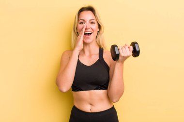 Sarışın, güzel bir kadın kendini mutlu hissediyor. Elleri ağızda, kocaman bağırıyor.