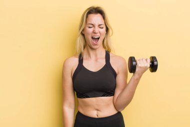 Sarışın, güzel bir kadın agresif bir şekilde bağırıyor, çok kızgın görünüyor.