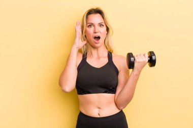 Sarışın, güzel bir kadın ellerini havaya kaldırıp çığlık atıyor.