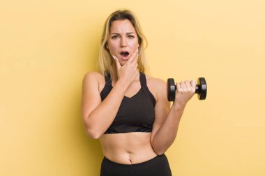 Sarışın, güzel bir kadın. Ağzı ve gözleri açık, elleri çenesinde.