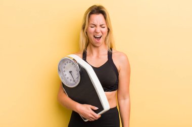 Sarışın, güzel bir kadın agresif bir şekilde bağırıyor, çok kızgın görünüyor.