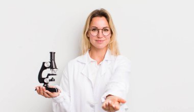 Sarışın, güzel bir kadın mutlu bir şekilde gülümsüyor ve bir konsept sunuyor.