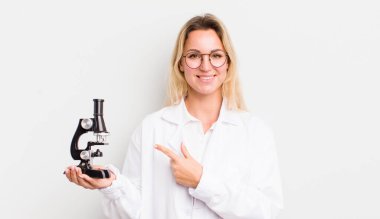 Sarışın, güzel bir kadın neşeyle gülümsüyor, mutlu hissediyor ve bir tarafı işaret ediyor.