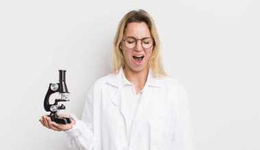 Sarışın, güzel bir kadın agresif bir şekilde bağırıyor, çok kızgın görünüyor.