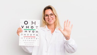 Sarışın, güzel bir kadın gülümsüyor ve arkadaş canlısı görünüyor, beş numarayı gösteriyor.