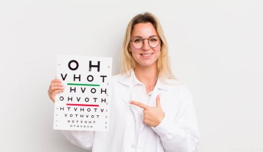 Sarışın, güzel bir kadın neşeyle gülümsüyor, mutlu hissediyor ve bir tarafı işaret ediyor.