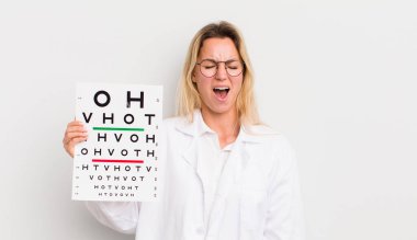 Sarışın, güzel bir kadın agresif bir şekilde bağırıyor, çok kızgın görünüyor.