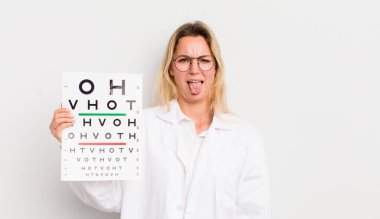 Sarışın, güzel bir kadın. Tiksinmiş, sinirli ve dilsiz.