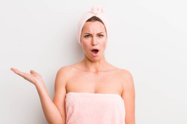 Güzel sarışın kadın şaşırmış ve şok olmuş görünüyor, çenesi düşmüş, elinde bir nesne tutuyor.