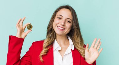 Güzel bir kadın mutlu bir şekilde gülümser, el sallar, hoş karşılar ve seni selamlar.