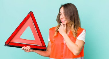 Güzel bir kadın mutlu, kendinden emin bir ifadeyle gülümsüyor, elleri çenesinde.