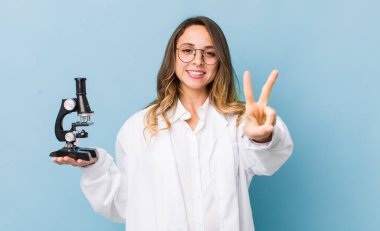 Güzel bir kadın gülümsüyor ve mutlu görünüyor. Zafer ya da barış işareti yapıyor.