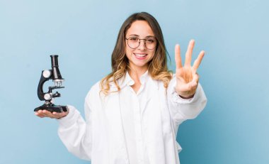 Güzel bayan gülümsüyor ve arkadaş canlısı görünüyor, üç numarayı gösteriyor.