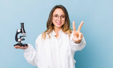 Güzel bayan gülümsüyor ve arkadaş canlısı görünüyor, iki numarayı gösteriyor.