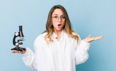 Güzel bir kadın şaşırmış ve şok olmuş görünüyor, çenesi düşmüş bir nesne tutuyor.