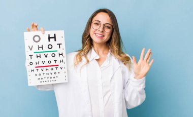 Güzel bir kadın mutlu bir şekilde gülümser, el sallar, hoş karşılar ve seni selamlar.