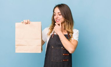 Güzel bir kadın mutlu, kendinden emin bir ifadeyle gülümsüyor, elleri çenesinde.