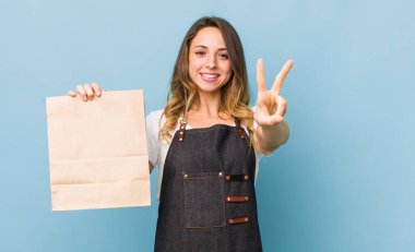 Güzel bir kadın gülümsüyor ve mutlu görünüyor. Zafer ya da barış işareti yapıyor.