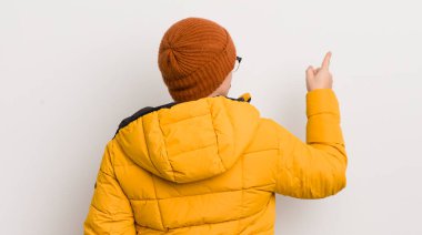 Beyaz duvarda paltosu olan genç yakışıklı bir adam.