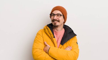 Beyaz duvarda paltosu olan genç yakışıklı bir adam.