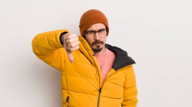 Beyaz duvarda paltosu olan genç yakışıklı bir adam.