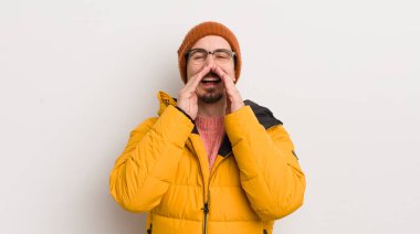 Beyaz duvarda paltosu olan genç yakışıklı bir adam.