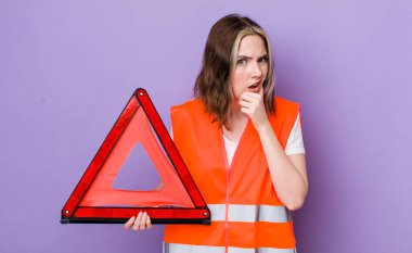 Ağzı ve gözleri açık, eli çenesinde güzel beyaz bir kadın. araba üçgeni kavramı