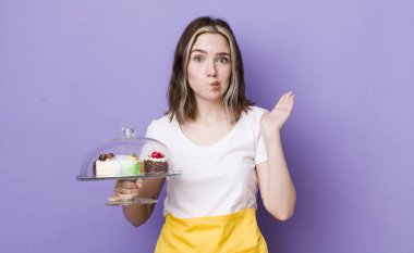 Kafası karışmış, kafası karışmış ve şüpheci bir beyaz kadın. Ev yapımı kek konsepti