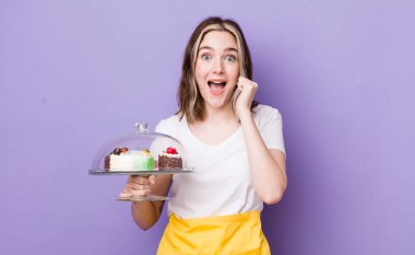Kafkasyalı bir kadın şoke olmuş, gülüyor ve başarıyı kutluyor. Ev yapımı kek konsepti