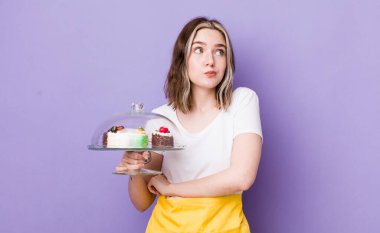 Beyaz bir kadın omuz silkiyor, kafası karışık ve kararsız. Ev yapımı kek konsepti