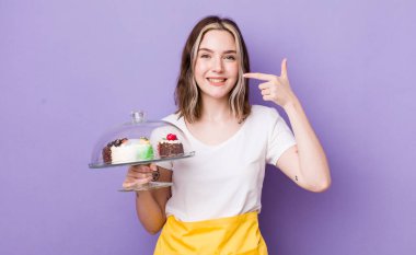 Güzel, beyaz bir kadın kendi gülüşünü işaret ediyor. Ev yapımı kek konsepti