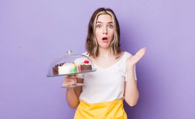 Kafkasyalı bir kadın şaşırmış ve şok olmuş görünüyor. Çenesi düşmüş ve elinde bir nesne var. Ev yapımı kek konsepti