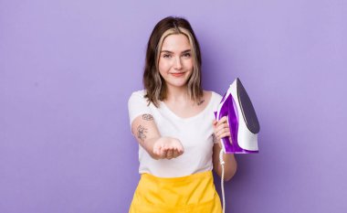 Güzel, beyaz bir kadın mutlu bir şekilde gülümsüyor ve bir konsept sunuyor. el demiri konsepti