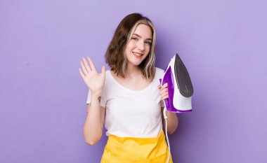 Güzel beyaz bir kadın mutlu bir şekilde gülümsüyor, el sallıyor, sizi selamlıyor ve selamlıyor. el demiri konsepti