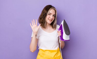 Güzel beyaz kadın gülümsüyor ve arkadaş canlısı görünüyor, beş numarayı gösteriyor. el demiri konsepti