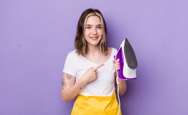 Güzel, beyaz bir kadın, neşeli bir şekilde gülümsüyor, mutlu hissediyor ve bir tarafı işaret ediyor. el demiri konsepti