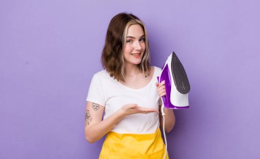 Güzel, beyaz bir kadın neşeyle gülümsüyor, mutlu hissediyor ve bir konsept gösteriyor. el demiri konsepti