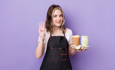 Güzel beyaz kadın gülümsüyor ve arkadaş canlısı görünüyor, üç numarayı gösteriyor. kahve konseptini kaldır.