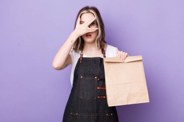 Güzel, beyaz bir kadın şok olmuş, korkmuş ya da korkmuş görünüyor. Yüzü elle kapatılmış. teslimat ve paket konsepti