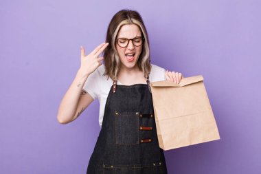 Oldukça beyaz bir kadın mutsuz ve stresli görünüyor, intihar jesti silah işareti yapıyor. teslimat ve paket konsepti