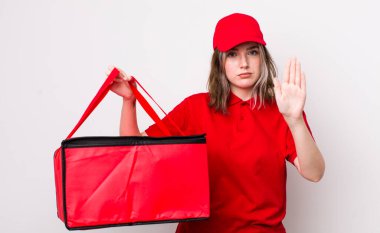 Beyaz kadın ciddi görünüyor. Avuç içinin açık olduğunu gösteriyor. Durdurma hareketi yapıyor. Pizza teslimatı kavramı